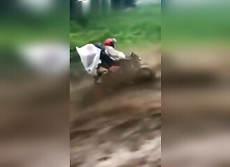 On a motorcycle, he tries to go up a flooded street
