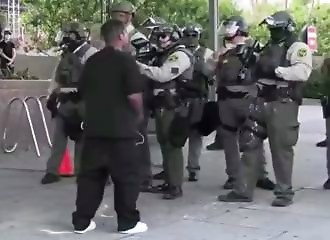 A demonstrator throws a can at a policeman and is tackled to the ground by a civilian