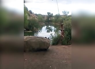 Une fille se balance au bout d’une corde pour plonger dans une rivière