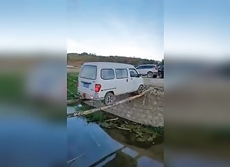 Sur deux troncs d'arbre, une camionnette traverse un canal à reculons