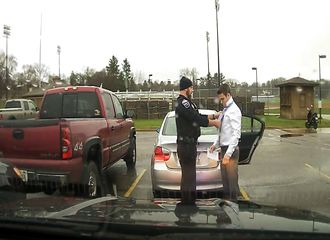 Un policier aide un automobiliste pris pour excès de vitesse à faire son nœud de cravate