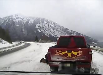 Une voiture dérape sur une route verglacée et manque de percuter un homme courbé sous une voiture (Alaska)